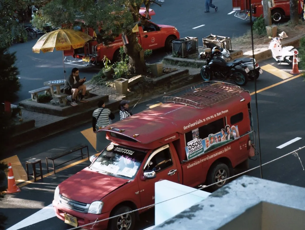 A red songthaew transport truck on the road to the Monk