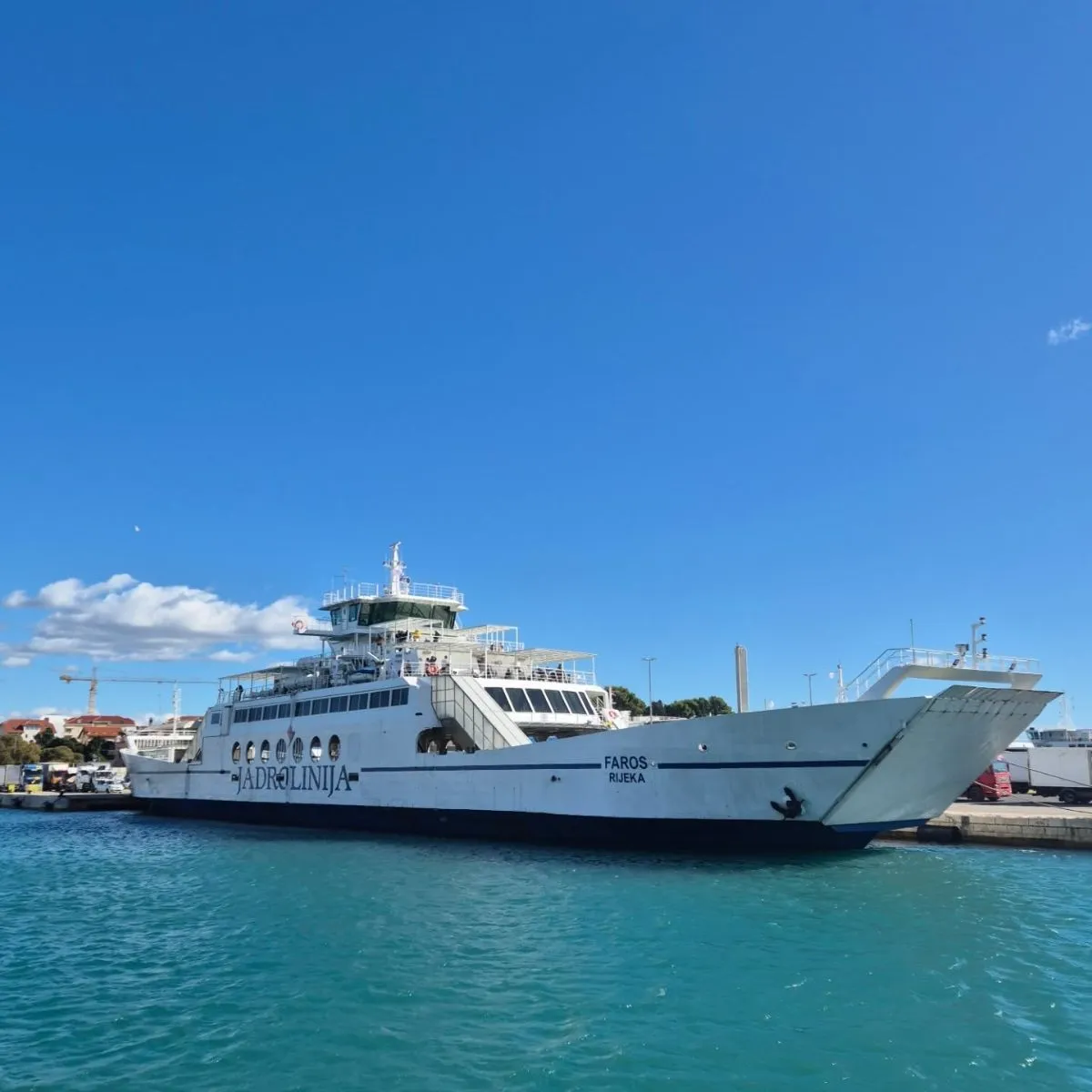A large white Jadrolinija ferry docked at a scenic Croatian harbor with turquoise water.