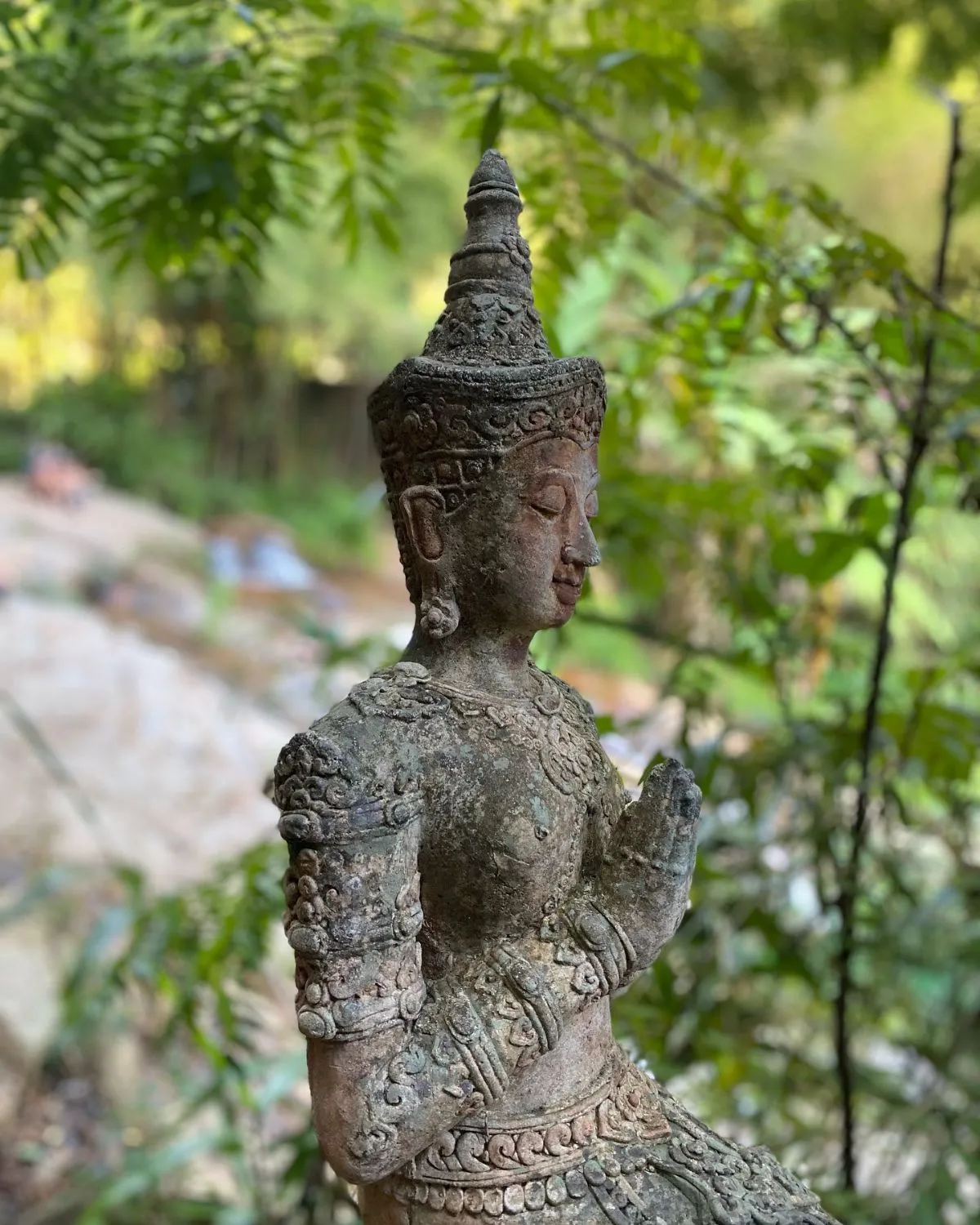 Moss-covered stone Buddha statue in the jungle at Wat Pha Lat Chiang Mai